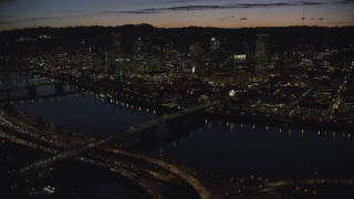 AX155_317 - 5.5K stock footage aerial video of a view across the Burnside Bridge and Willamette River of Downtown Portland and the White Stag Sign, Oregon, at night
