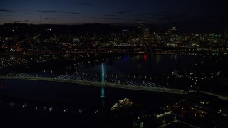 AX155_323E - 5.5K aerial stock footage flying by Tilikum Crossing, with Downtown Portland skyline in the distance, Oregon, night