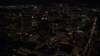 AX155_328E - 5.5K aerial stock footage flying over KOIN Center and Wells Fargo Center, and reveal city squares at night in Downtown Portland, Oregon