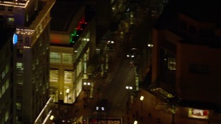 AX155_388E - 5.5K aerial stock footage orbiting top of Jackson Tower at nighttime in Downtown Portland, Oregon, reveal and track a drone