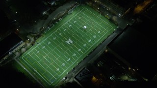 AX155_435E - 5.5K aerial stock footage approaching football practice at Portland State University sports field at night, Downtown Portland, Oregon