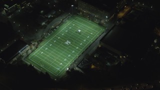 AX155_437 - 5.5K stock footage aerial video of a reverse view of football practice at Portland State University sports field at night, reveal I-405, Downtown Portland, Oregon