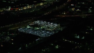 AX155_450 - 5.5K aerial stock footage flying by a packed parking garage at night in Tigard, Oregon