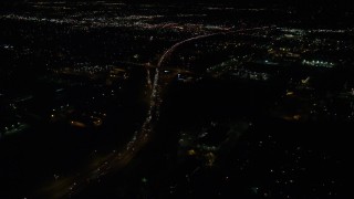 AX155_463 - 5.5K aerial stock footage following light traffic on Highway 217 to approach warehouse buildings at night, Beaverton, Oregon