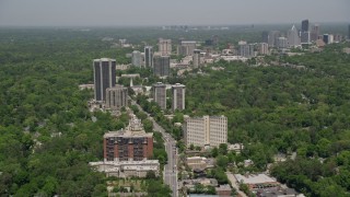 AX36_049E - 4.8K aerial stock footage following Peachtree Road past office buildings and wooded area, Buckhead, Atlanta, Georgia