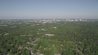AX38_033 - 4.8K aerial stock footage flying over a junkyard and trees, tilt up revealing Midtown Atlanta, Georgia