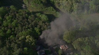 AX38_036E - 4.8K aerial stock footage orbiting smoke from a burning home in a wooded area, West Atlanta