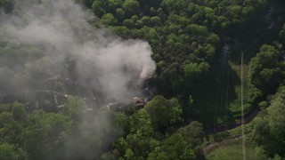 AX38_048E - 4.8K aerial stock footage approach and tilt to smoke rising from a house fire in a wooded area, West Atlanta, Georgia