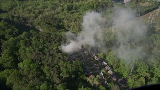 AX38_057 - 4.8K aerial stock footage of smoke rising from a house fire in a wooded area, West Atlanta