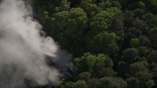 AX38_058 - 4.8K aerial stock footage of smoke rising from a house fire in a wooded area, West Atlanta