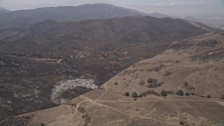 AX42_012E - 5K aerial stock footage of burned rural homes near the edge of wildfire damage, Santa Monica Mountains, California