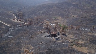 AX42_014 - 5K stock footage aerial video flyby fire-ravaged rural homes surrounded by wildfire damage in the Santa Monica Mountains, California