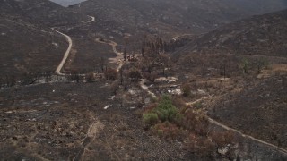 AX42_014E - 5K aerial stock footage flyby fire-ravaged rural homes surrounded by wildfire damage in the Santa Monica Mountains, California