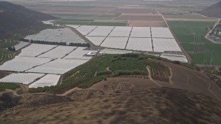 AX42_019E - 5K aerial stock footage flyby orchard, crop fields and greenhouses, Camarillo, California