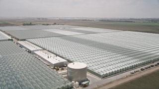 AX42_032 - 5K aerial stock footage of flying by large greenhouses, Camarillo, California