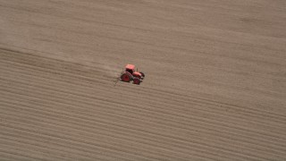 AX42_035 - 5K aerial stock footage track a tractor tilling a field, Camarillo, California