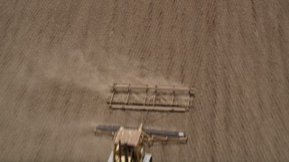 AX42_038 - 5K aerial stock footage fly over farm field to approach a tractor tilling a field, Camarillo, California