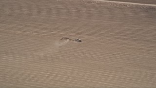 AX42_046 - 5K aerial stock footage track a tractor tilling the soil of a farm field, Camarillo, California