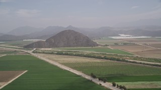 AX42_047 - 5K aerial stock footage flyby farmland and country roads around a steep hill, Camarillo, California