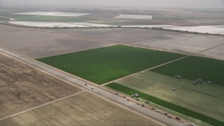 AX42_049 - 5K aerial stock footage flyby a green feeds and tractors beside a country road, Camarillo, California