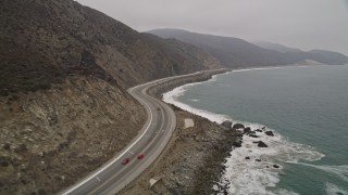 AX42_059E - 5K aerial stock footage of following low over the coast beside Highway 1, Point Mugu, California