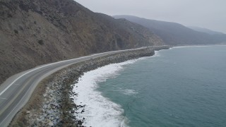 AX42_060 - 5K stock footage aerial video fly low to follow light traffic on Highway 1, Point Mugu, California