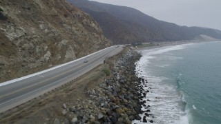 AX42_062 - 5K stock footage aerial video of flying low over waves and following coastal Highway 1, and pan to ocean, Malibu, California