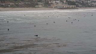 AX42_077E - 5K aerial stock footage approach surfers in the Pacific Ocean off the coast of Malibu, California