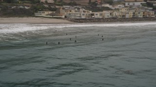 AX42_079 - 5K aerial stock footage track a group of surfers in the ocean near a beach, Malibu, California