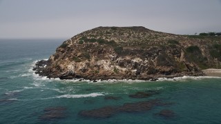 AX42_089 - 5K aerial stock footage of blue waters at the bottom of the cliffs of Point Dume, Malibu, California