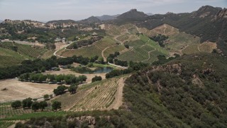 AX42_101E - 5K aerial stock footage flyby rock formations atop hills, vineyards, and a country road in Malibu, California