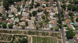 AX42_120 - 5K aerial stock footage of reverse view of suburban homes, school, a nursery, and apartment buildings, Canoga Park, California