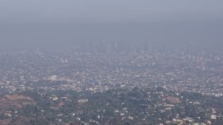 AX43_001 - 4K aerial stock footage approaching and flying over a tree atop a hill to reveal Downtown Los Angeles, California 
