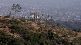 AX43_010 - 4K aerial stock footage flying by Griffith Observatory, Downtown Los Angeles skyline blanketed in fog in the background, Los Angeles