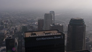 AX43_027E - 4K aerial stock footage flying by US Bank Tower, and over City National Plaza and Paul Hastings  Tower on a foggy day, Downtown Los Angeles, California
