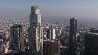 AX43_033 - 4K aerial stock footage flying between US Bank Tower and Aon Center to focus on city sprawl in the background, Downtown Los Angeles, California