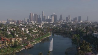 AX43_043 - 4K stock footage aerial video flying over Echo Park Lake fountain to approach Downtown Los Angeles skyline, California