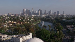 AX43_043E - 4K aerial stock footage flying over Echo Park Lake fountain to approach Downtown Los Angeles skyline, California