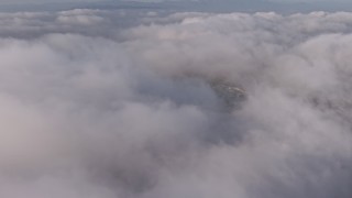 AX43_052 - 4K aerial stock footage flying over a dense marine layer with a break in the clouds, Los Angeles, California