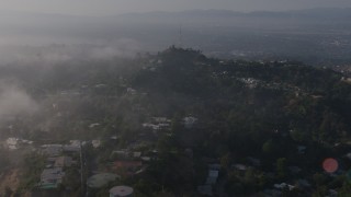 AX43_059 - 4K stock footage aerial video flying over marine layer to approach upscale, hillside homes near a radio tower, Beverly Hills, California