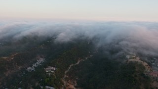 AX44_005 - 4K aerial stock footage of fog rolling in over the hills in Sherman Oaks, California, sunset