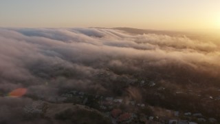 AX44_010E - 4K aerial stock footage flying over marine layer above the hills, Studio City, California, sunset