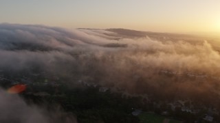 AX44_012 - 4K aerial stock footage flying over marine layer above the hills, Studio City, California, sunset