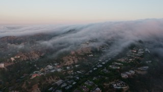 AX44_013 - 4K aerial stock footage of a marine layer rolling over the hills and homes, Studio City, California, sunset