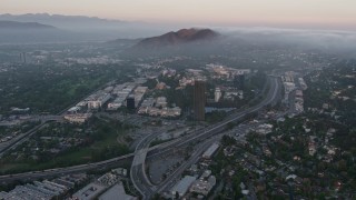 AX44_017E - 4K aerial stock footage of fog rolling near Universal City, Universal Studios, California, sunset