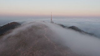 AX44_020E - 4K aerial stock footage of the Marine Layer rolling over Hollywood Hills, Los Angeles, California, sunset