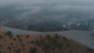 AX44_023 - 4K aerial stock footage orbiting Hollywood Sign and radio tower cloaked in Marine Layer, California, sunset
