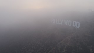 AX44_023E - 4K aerial stock footage orbiting Hollywood Sign and radio tower cloaked in Marine Layer, California, sunset