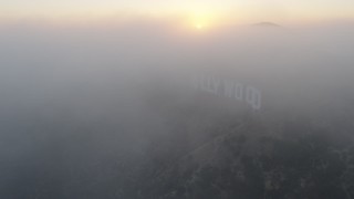 AX44_024 - 4K aerial stock footage of Hollywood sign covered in thick marine layer, Los Angeles, California, sunset