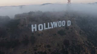 AX44_026E - 4K aerial stock footage approaching radio tower peeking through marine layer, reveal the Hollywood Sign, California, sunset